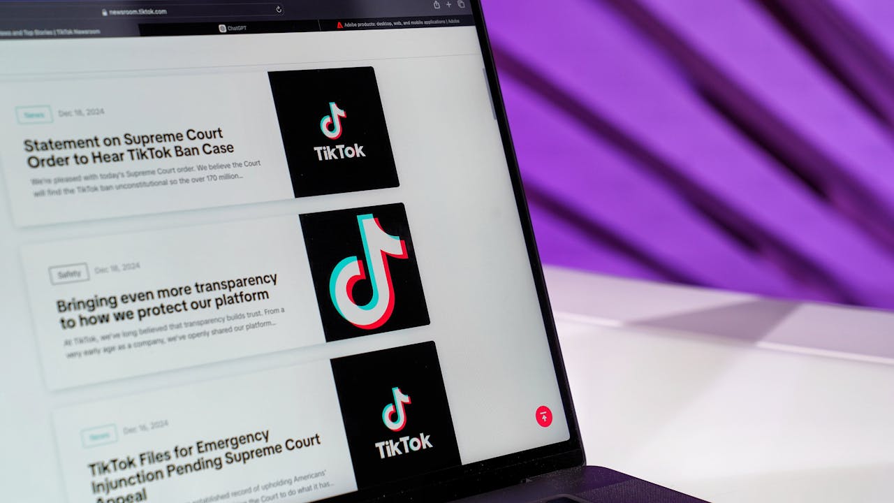 Close-up of laptop screen showing TikTok news articles with a purple background.